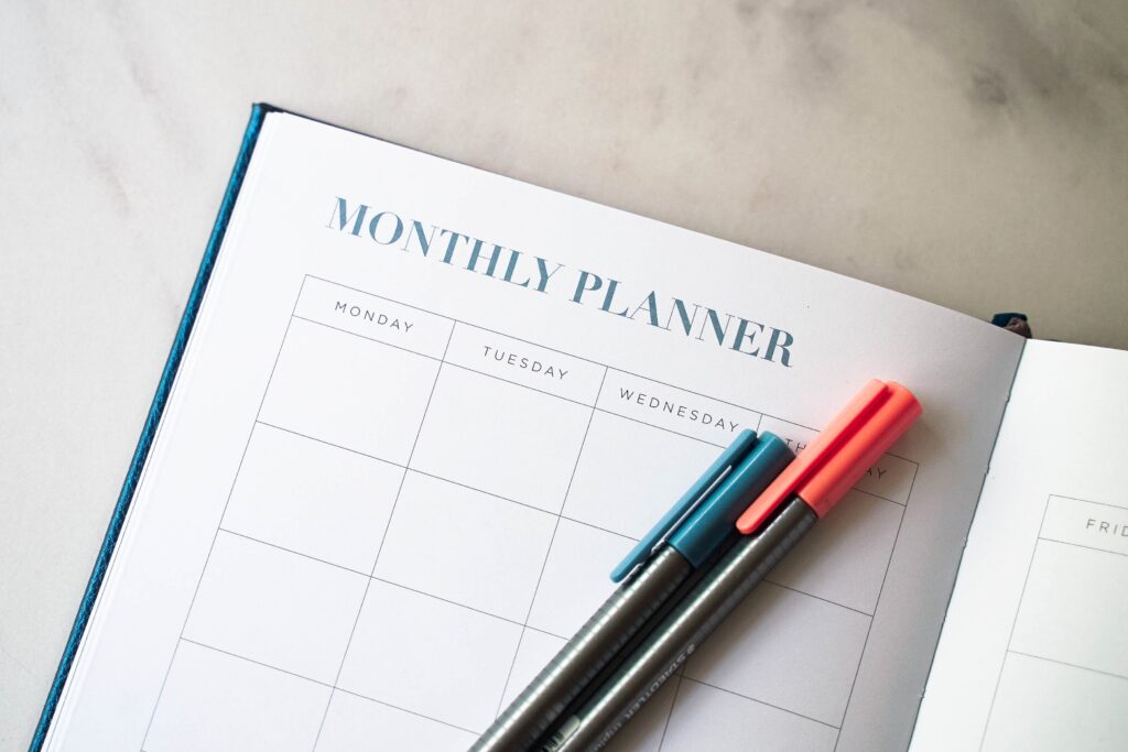 A blank page in a monthly planner with red and green markers sitting on it.  