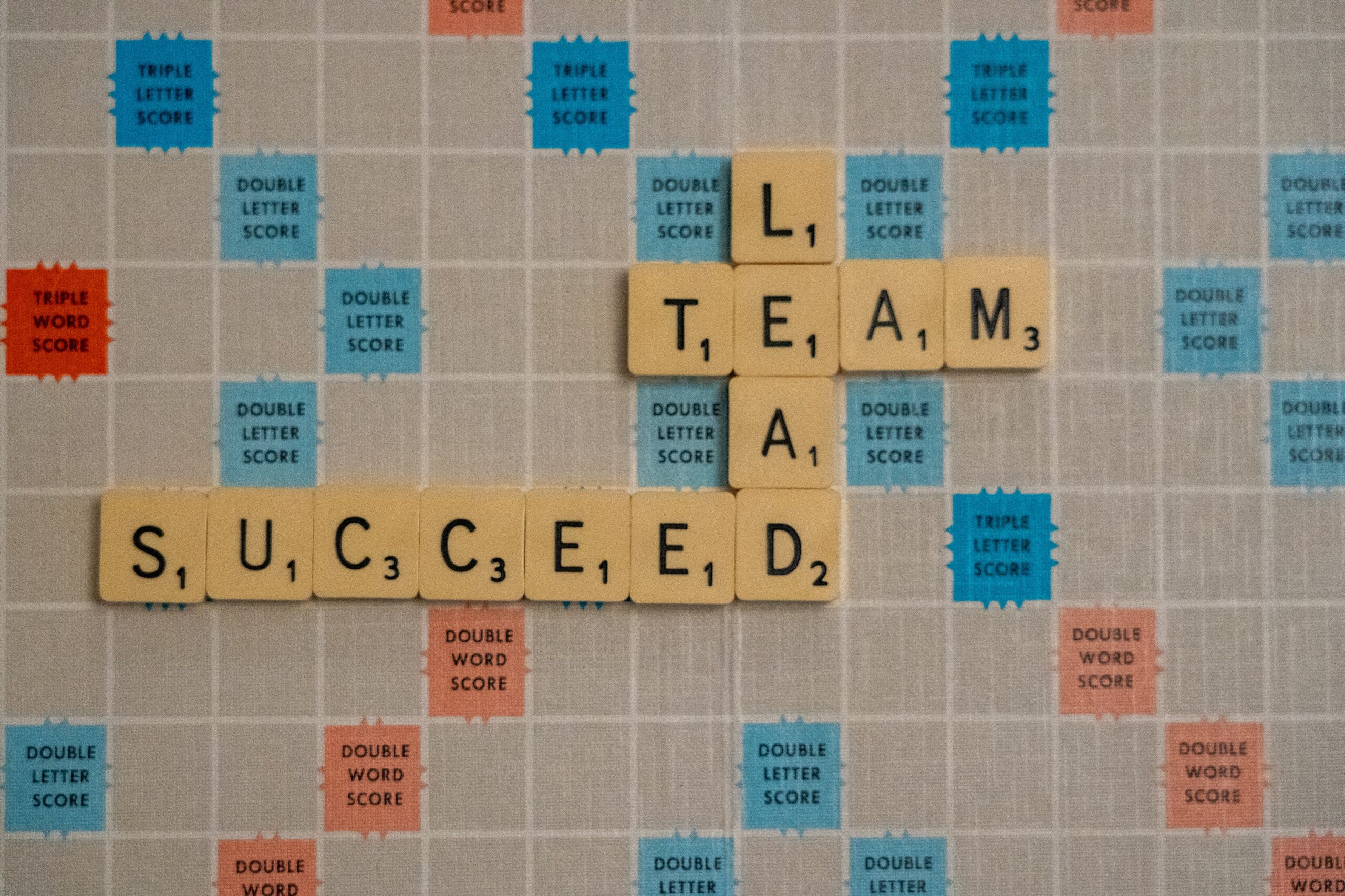 A board game features the words lead, team, and succeed.