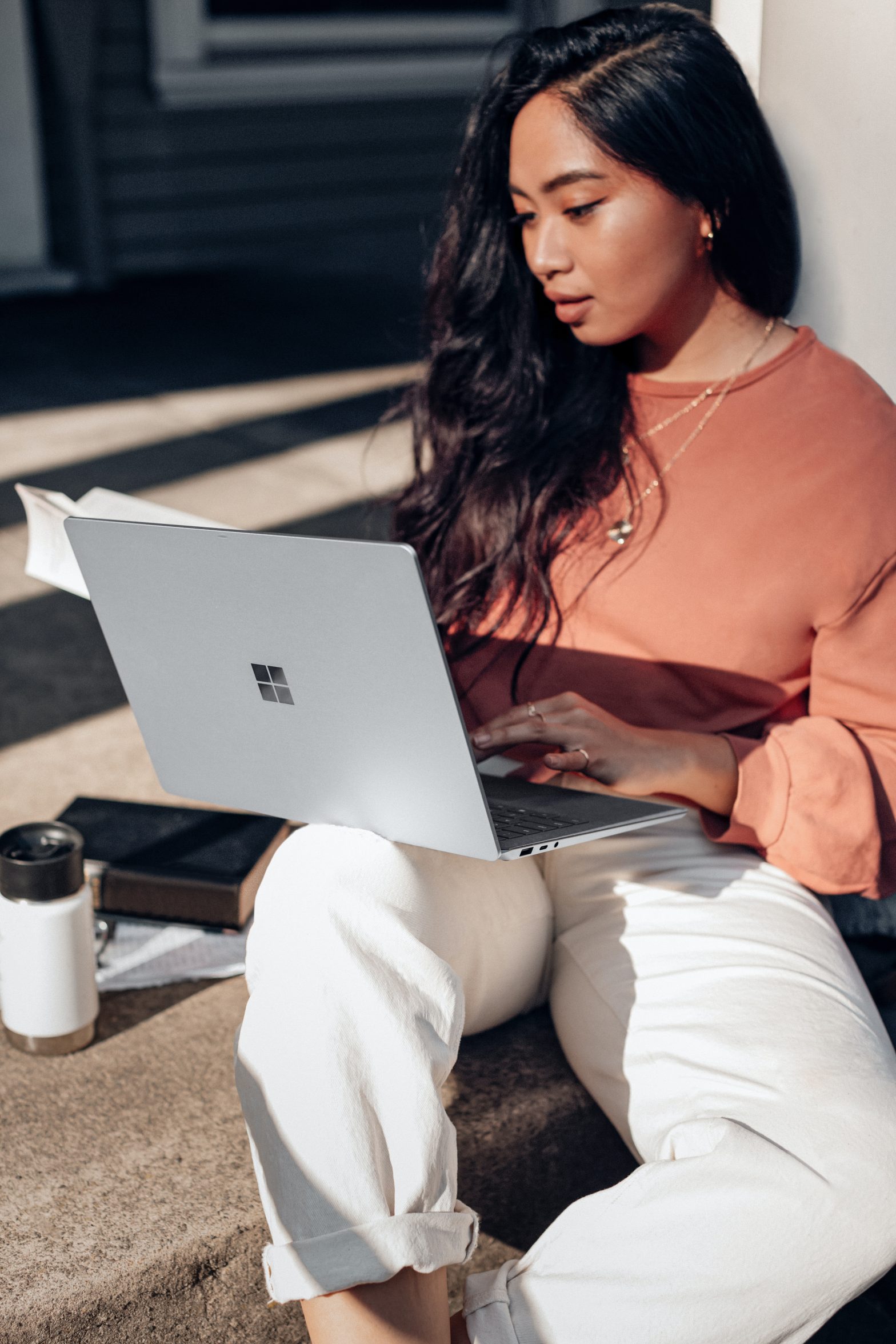 A racialized woman sits in front of a laptop working.